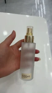 Chai xịt thủy tinh mờ 100ml vòi vàng cầm trên tay